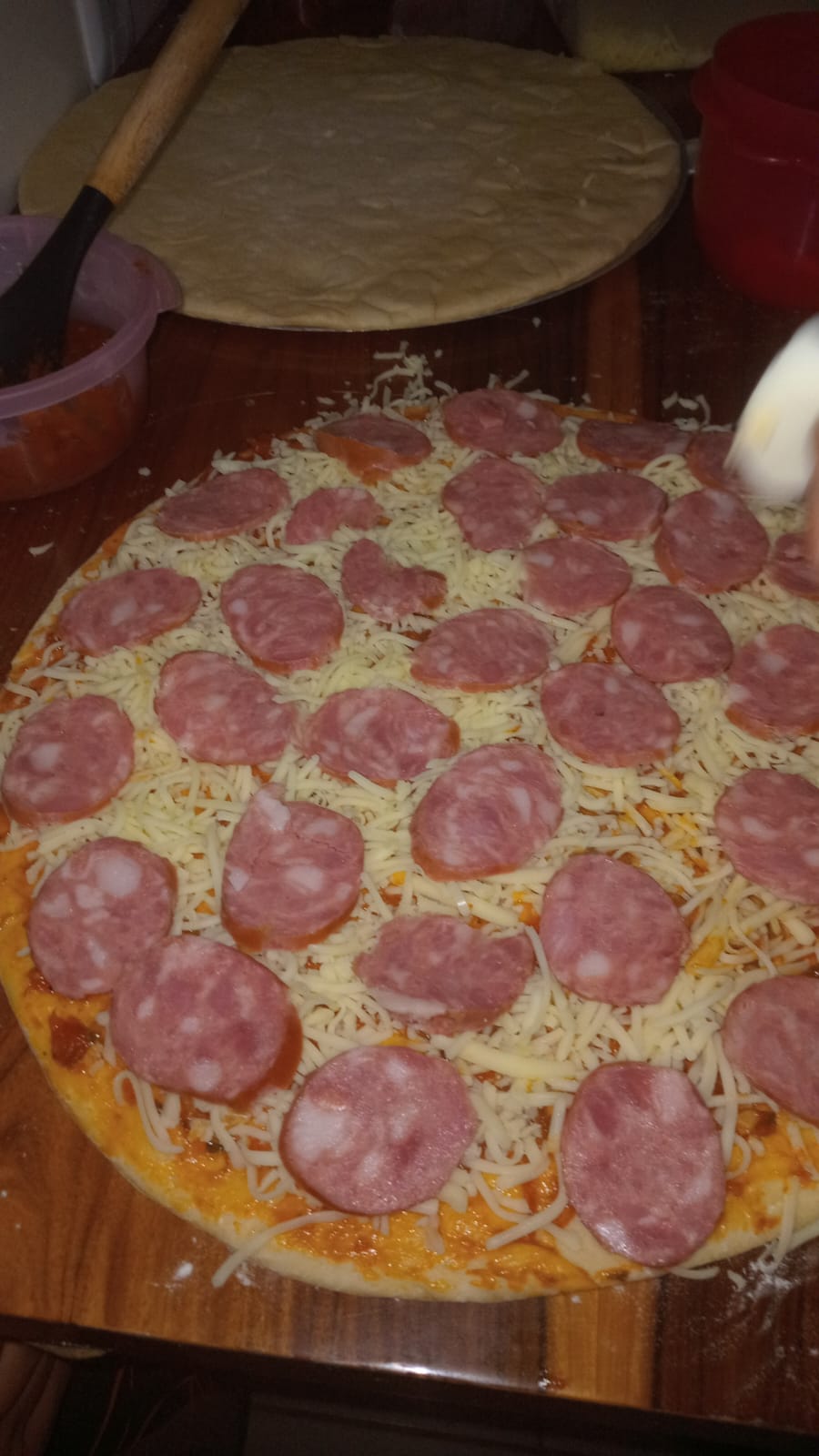 Pizza de calabresa sendo montada antes de ir ao forno